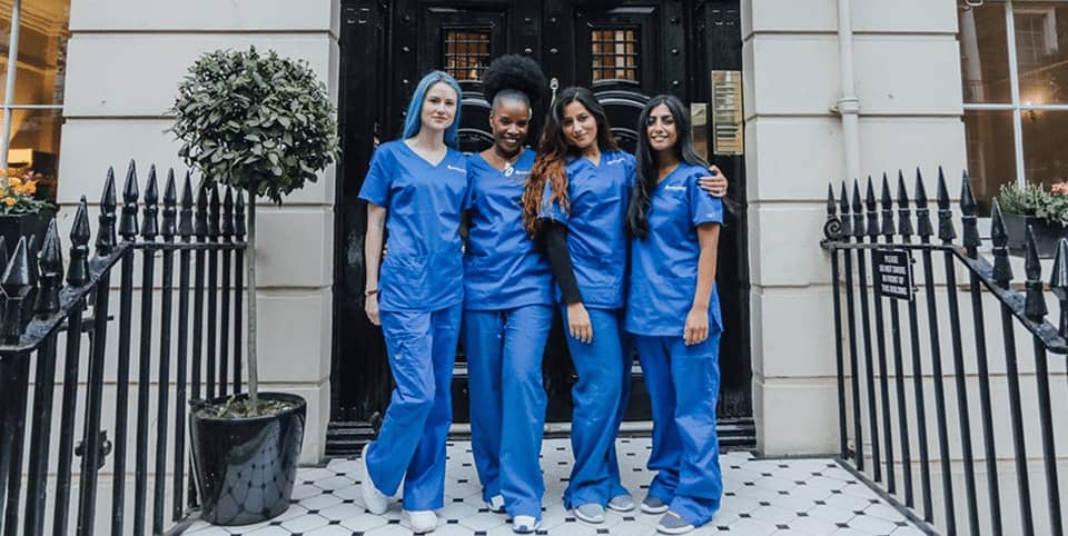 Four nurses in blue scrubs outside a Georgian clinic entrance for CoolSculpting fat freezing in Amsterdam