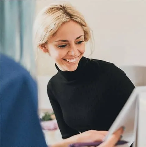 Smiling blonde woman during a consultation at a desk at Cool Clinic, CoolSculpting fat freezing Amsterdam